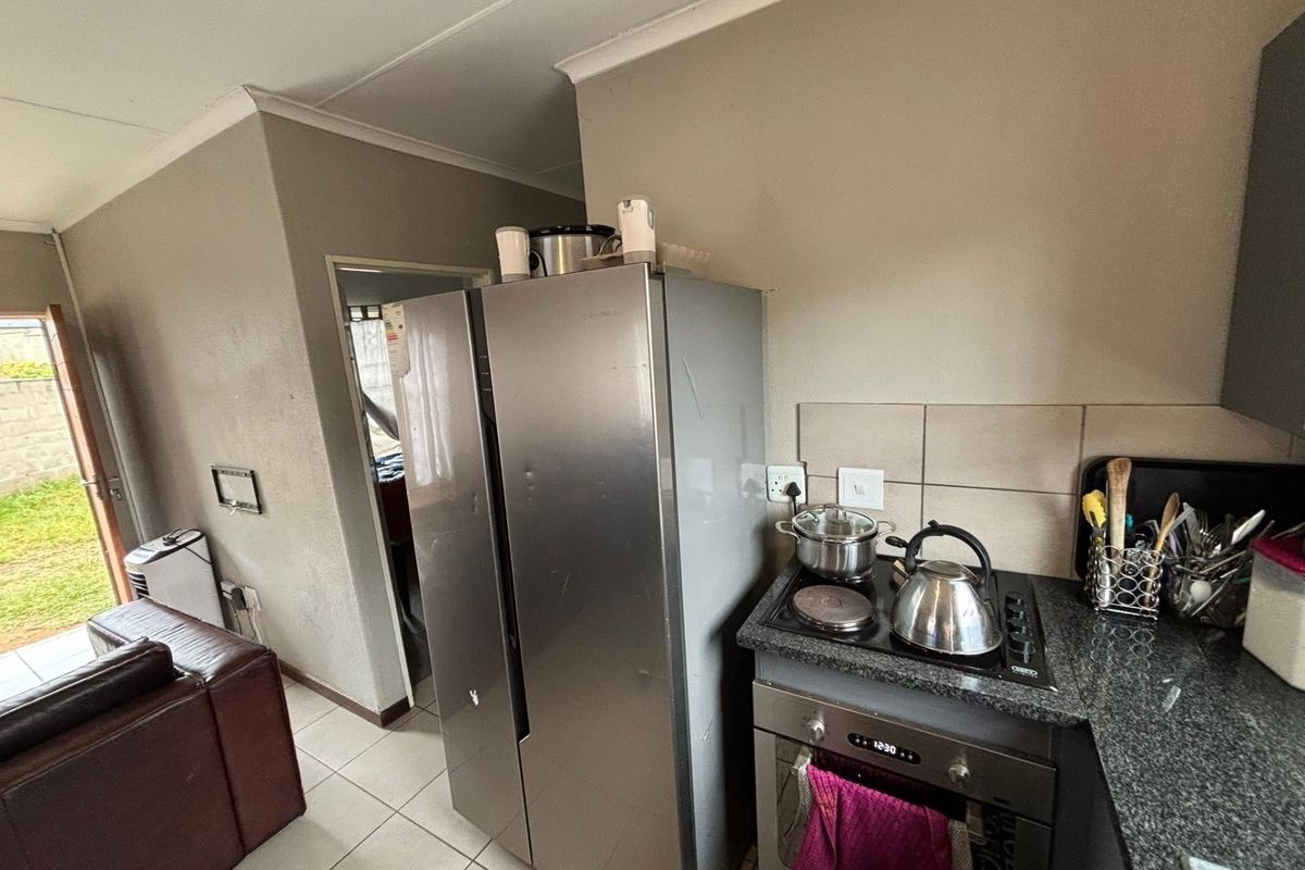A functional kitchen area featuring granite countertops, a built-in oven, and an electric hob with tiled backsplash and flooring.