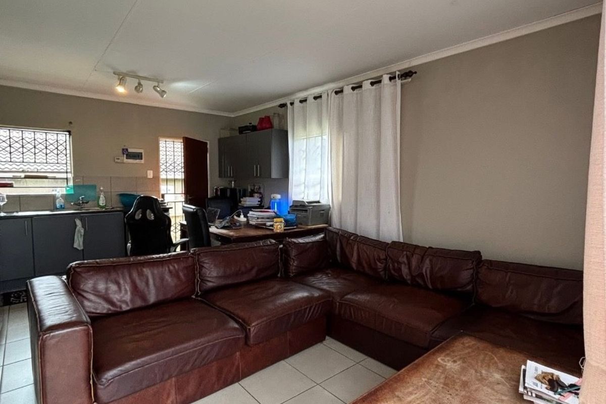 Open plan living area featuring tiled flooring and an integrated kitchen space with cabinetry and sink.