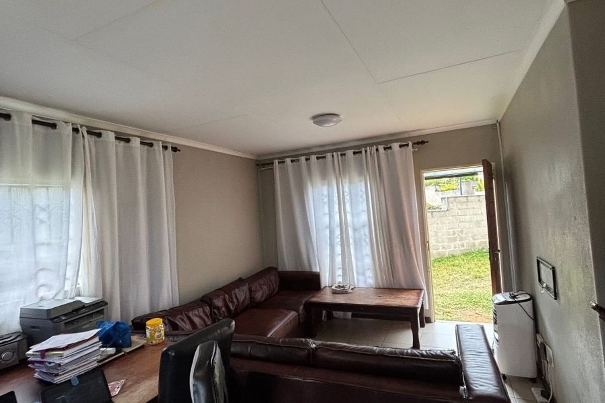 A functional living room featuring tiled flooring, coved ceilings, and direct access to the rear garden area.
