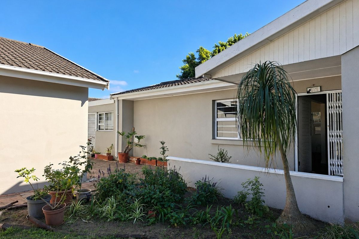 A view of the rear exterior featuring a paved patio area, tiled roofing, and secure access points to the home.
