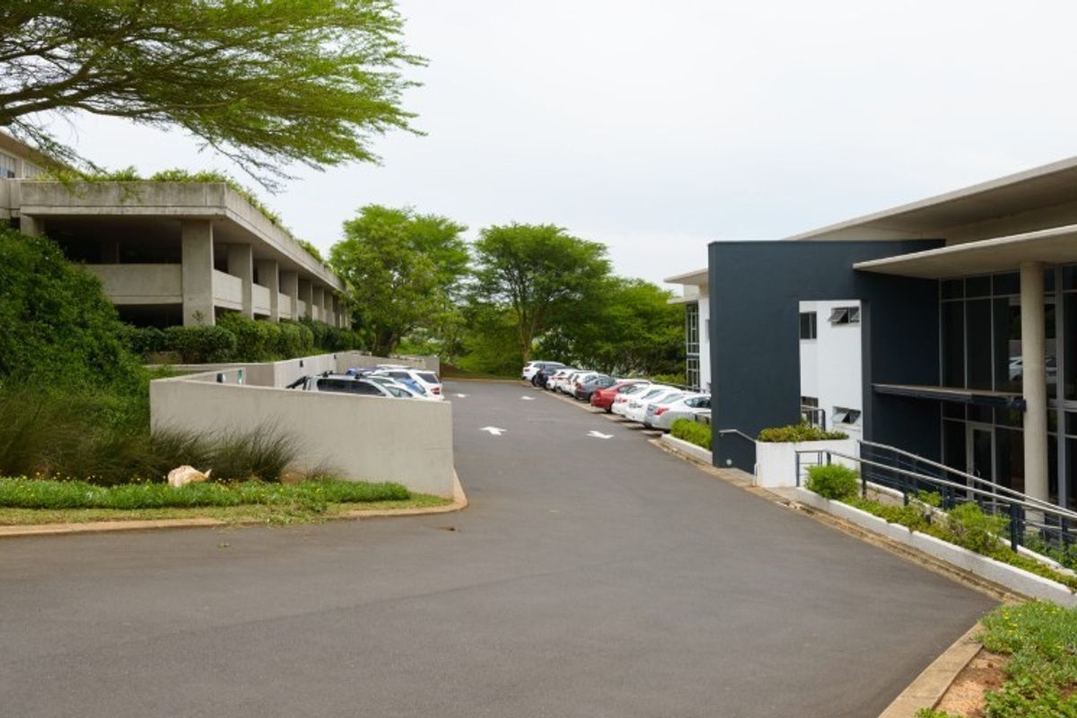 Exterior view of an industrial property featuring a paved driveway, concrete retaining walls, and modern building facades with landscaped surroundings.