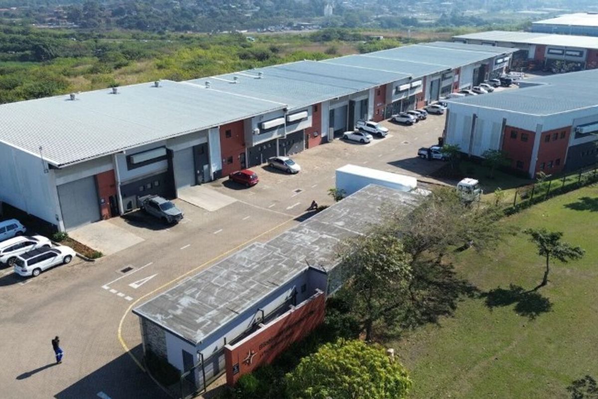 Aerial view of an industrial warehouse complex featuring multiple units, roller shutter doors, a paved yard, and a secure gated entrance.