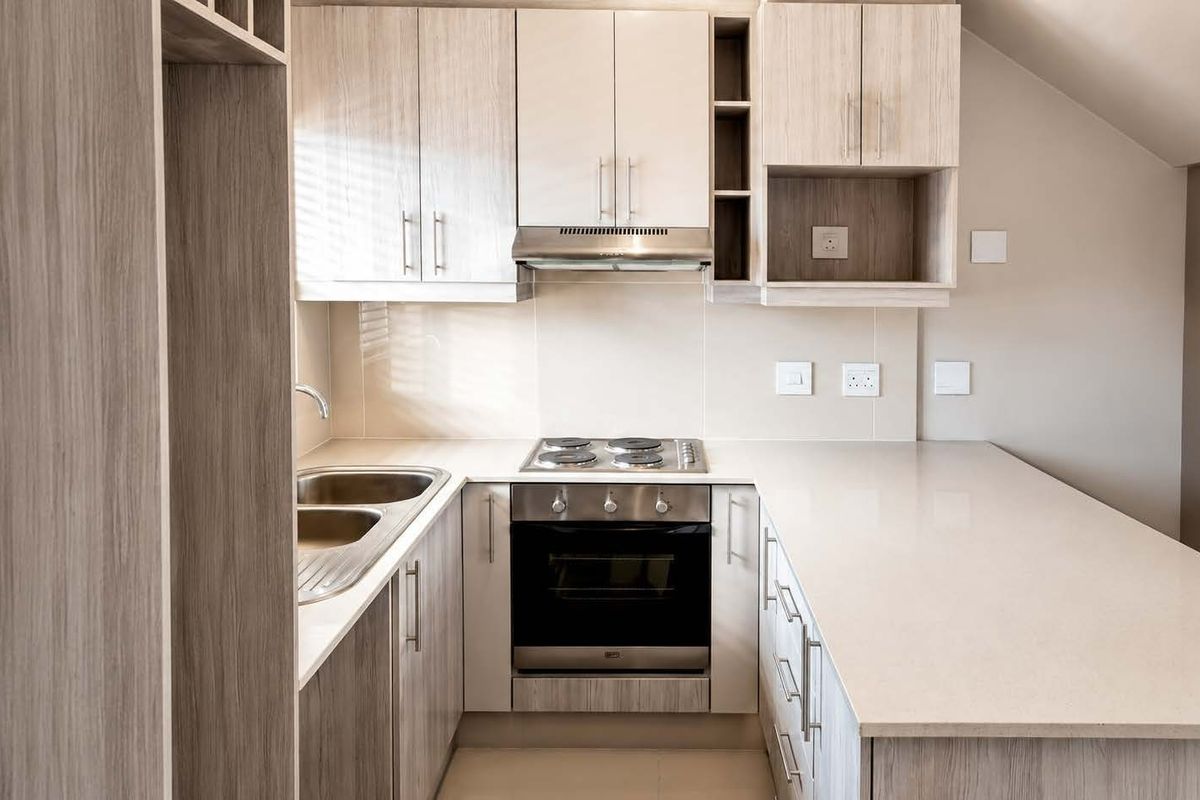 Modern kitchen featuring light wood-grain cabinetry, stone countertops, integrated stainless steel oven, electric hob, and extractor fan in a clean, contemporary layout.