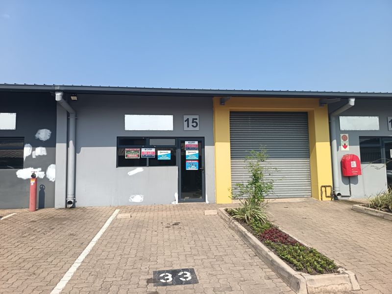 Front elevation of an industrial unit featuring a roller shutter door, paved parking bay, and exterior fire safety equipment.