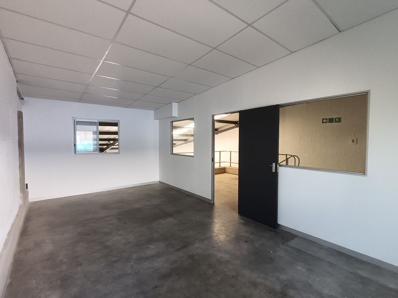 A clean, empty industrial office space featuring a suspended ceiling, polished concrete floors, and internal glass partitioning for natural light.