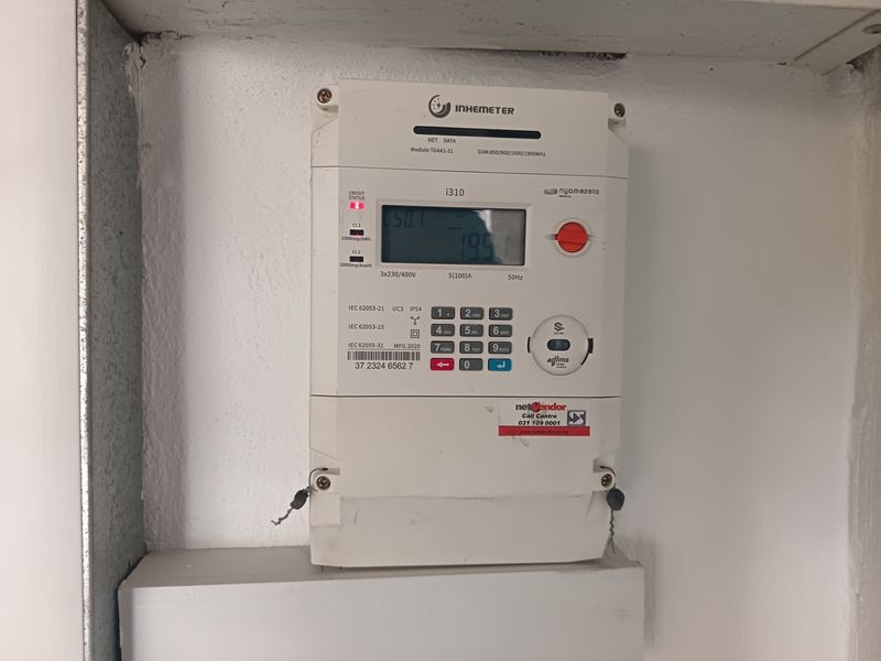 A wall-mounted digital prepaid electricity meter installed in a utility area.