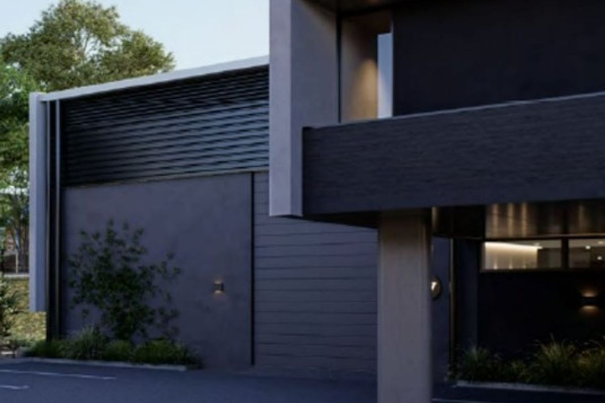 Modern industrial building exterior featuring a sleek dark facade, concrete structural elements, and integrated exterior lighting.