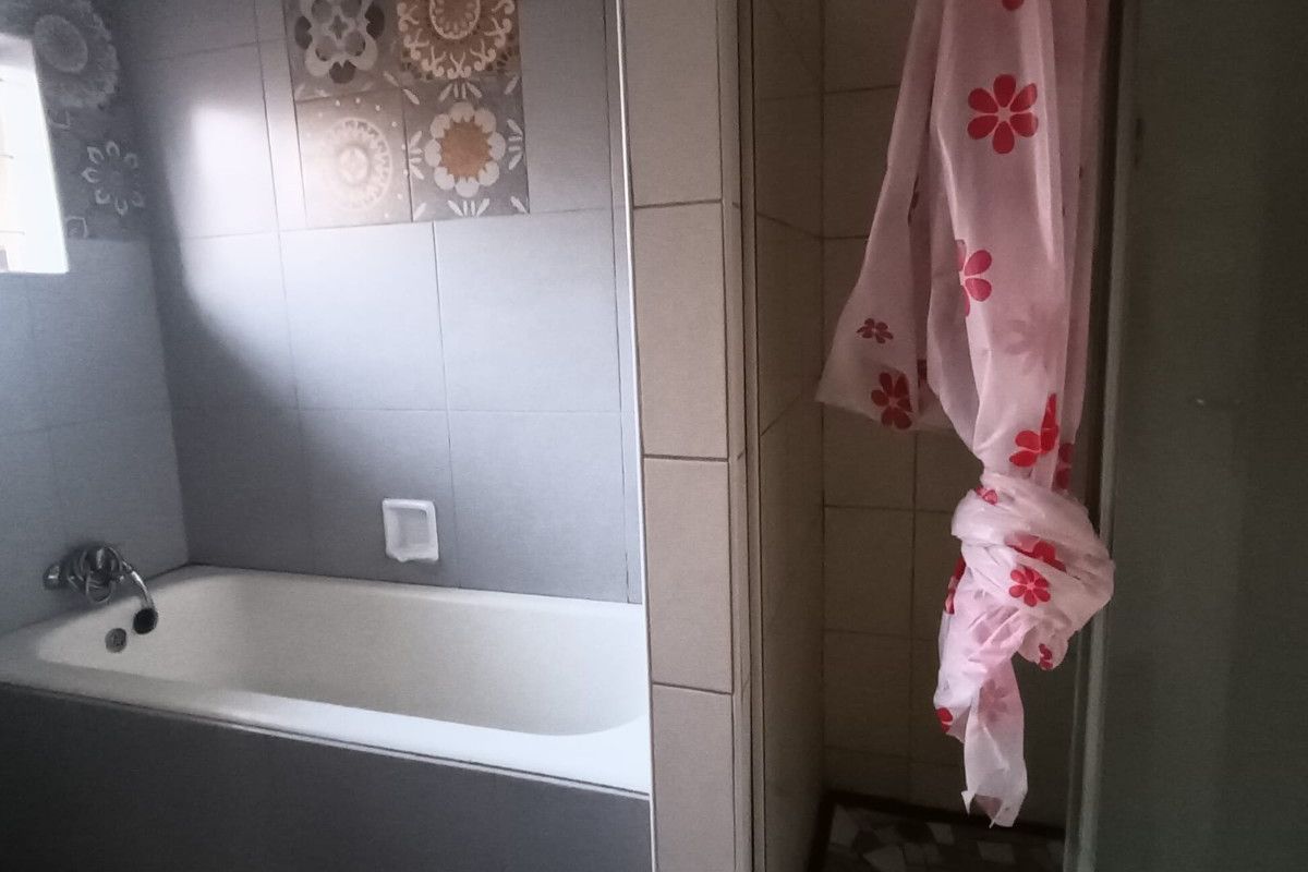 A functional bathroom featuring a built-in bathtub, a separate shower enclosure, and neutral wall tiling with decorative accent tiles.