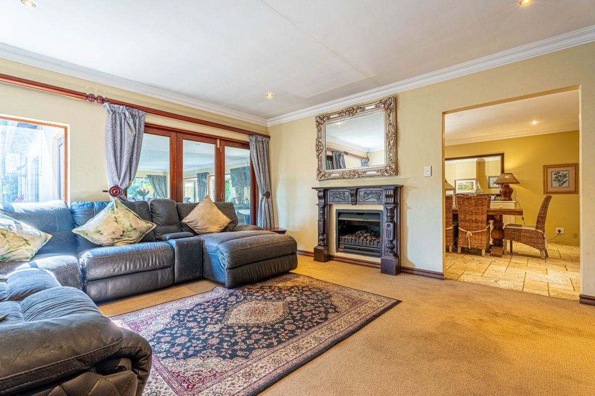 A comfortable living room featuring a decorative fireplace with a mantelpiece, crown molding, and sliding glass doors leading to an adjacent space.