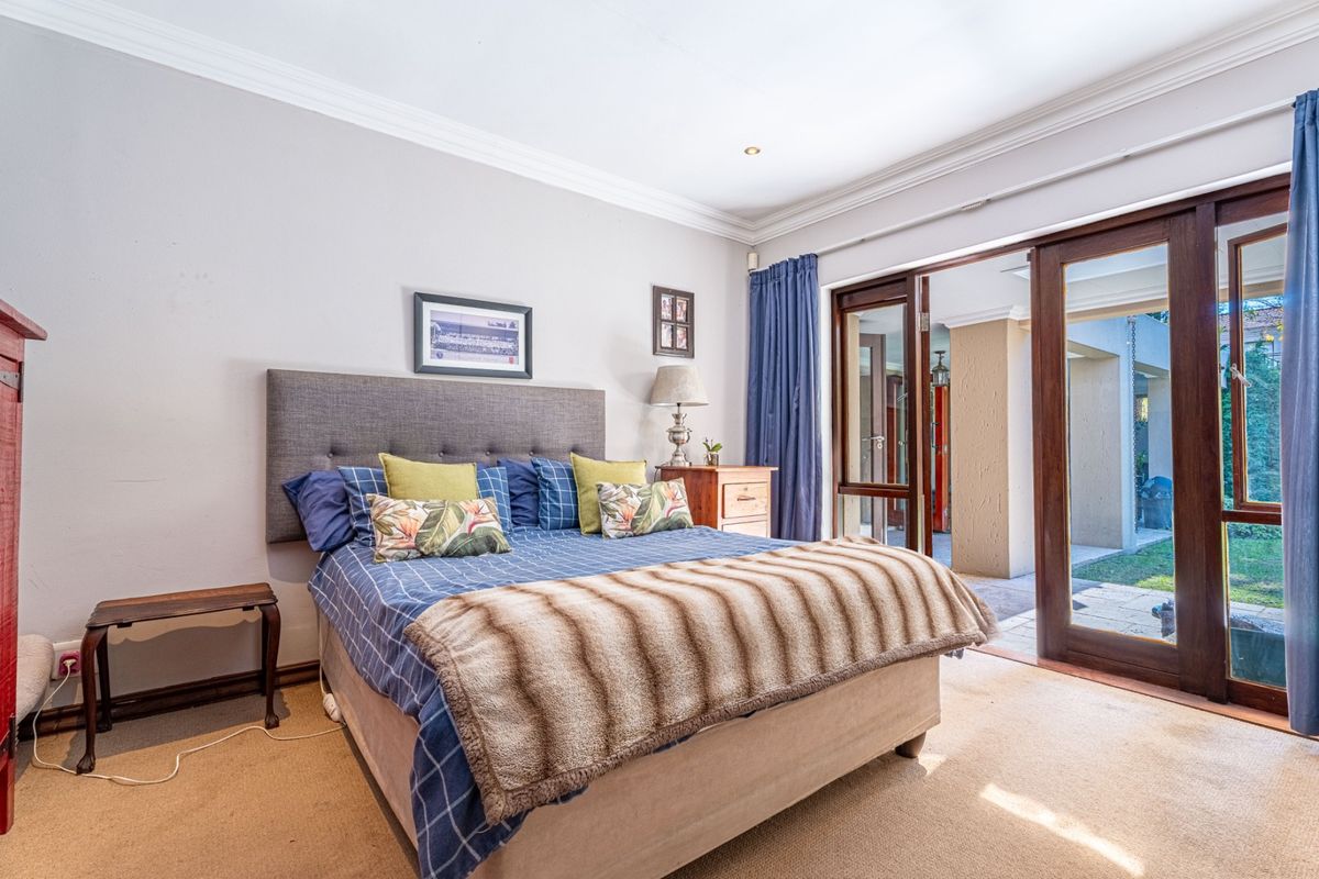 A well-lit bedroom featuring neutral walls, crown molding, and large sliding glass doors that provide direct access to the outdoor patio area.