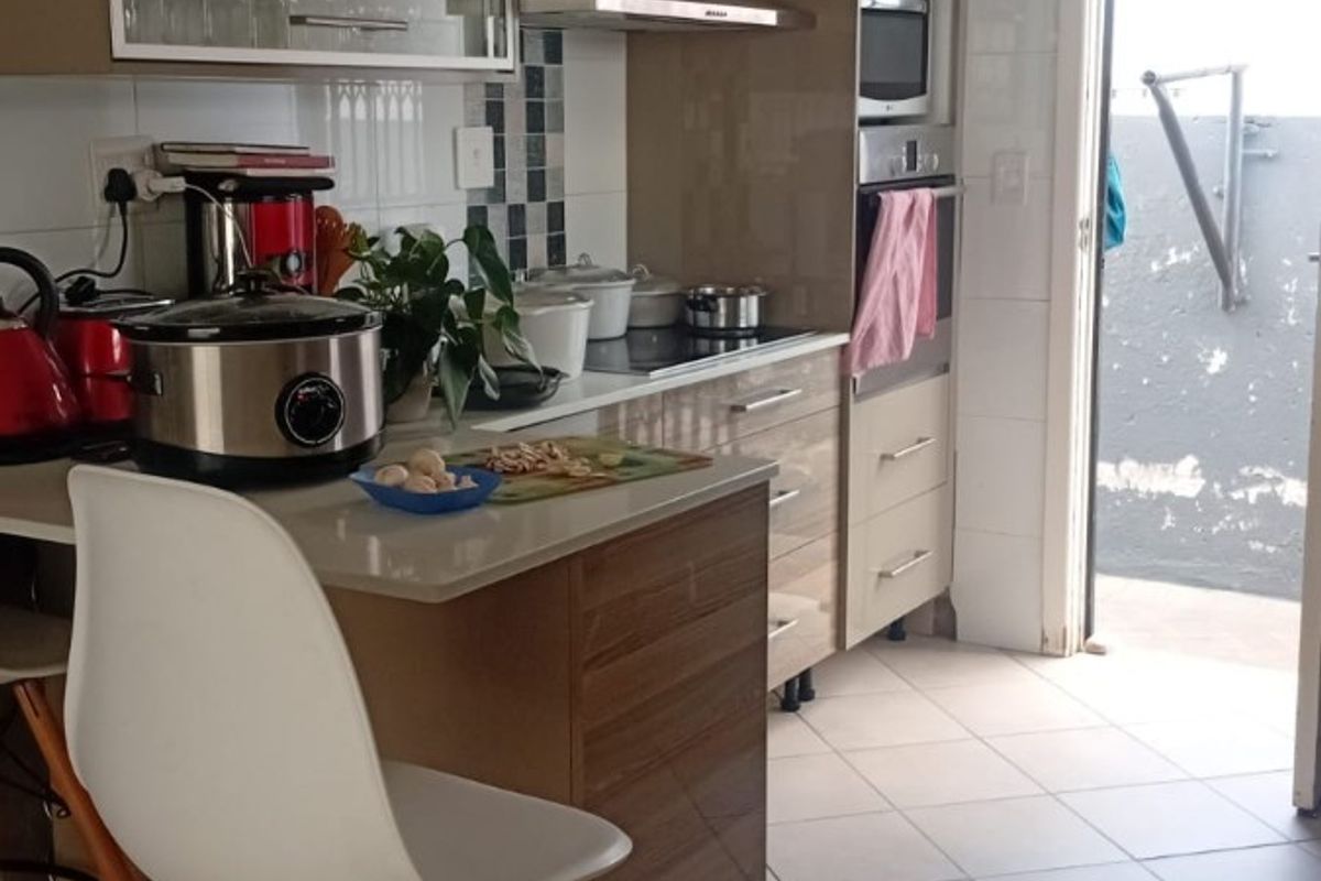 Modern kitchen featuring sleek cabinetry, built-in oven and microwave, ceramic hob, extractor fan, and tiled flooring with direct access to an outdoor area.