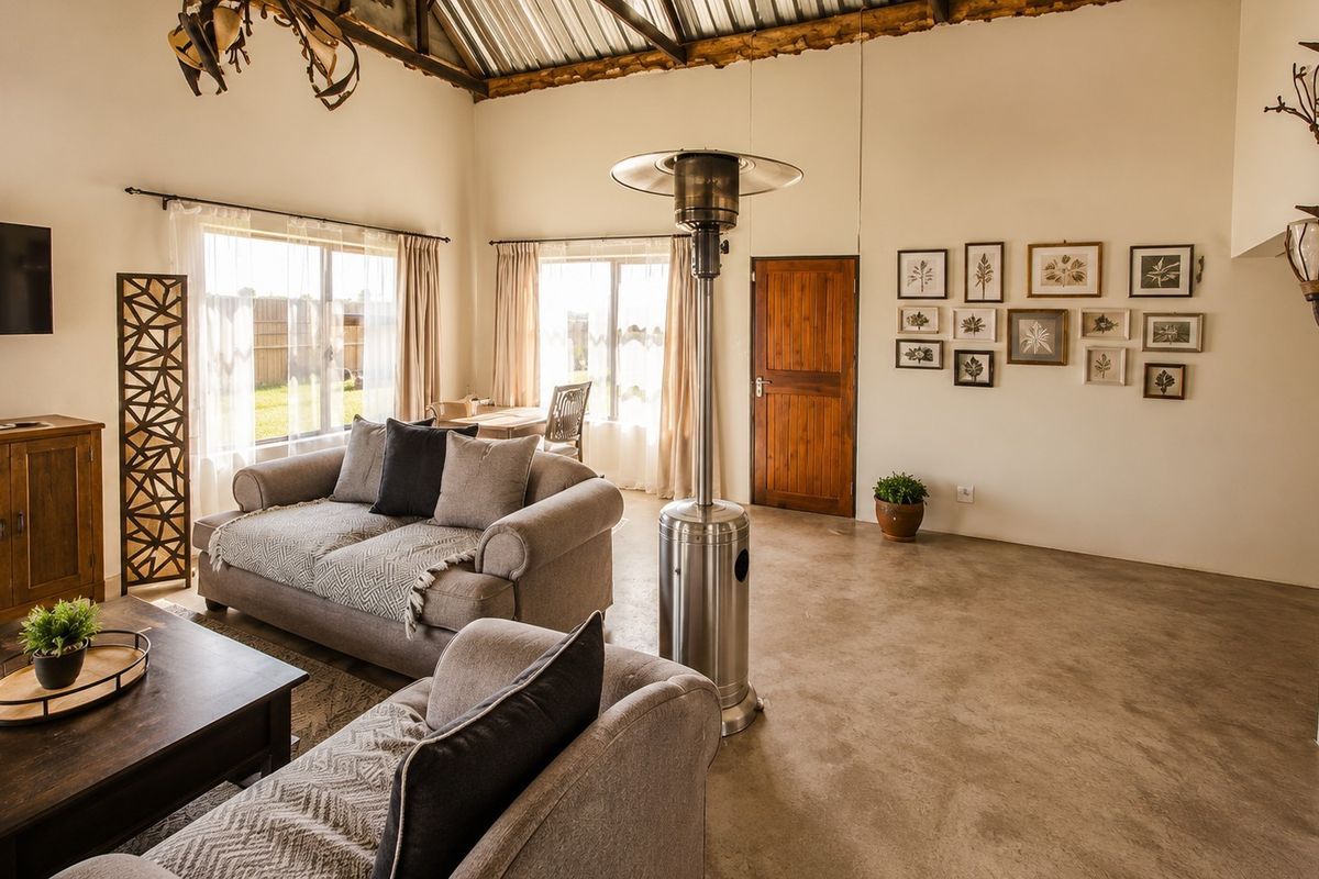 Spacious living area featuring high vaulted ceilings with exposed timber rafters, polished concrete floors, and natural light through large windows.