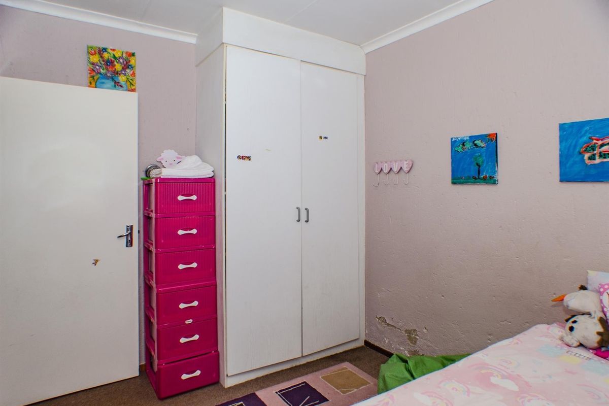 A bedroom featuring a built-in wardrobe and coving, showing visible signs of wall surface damage and peeling paint requiring maintenance.