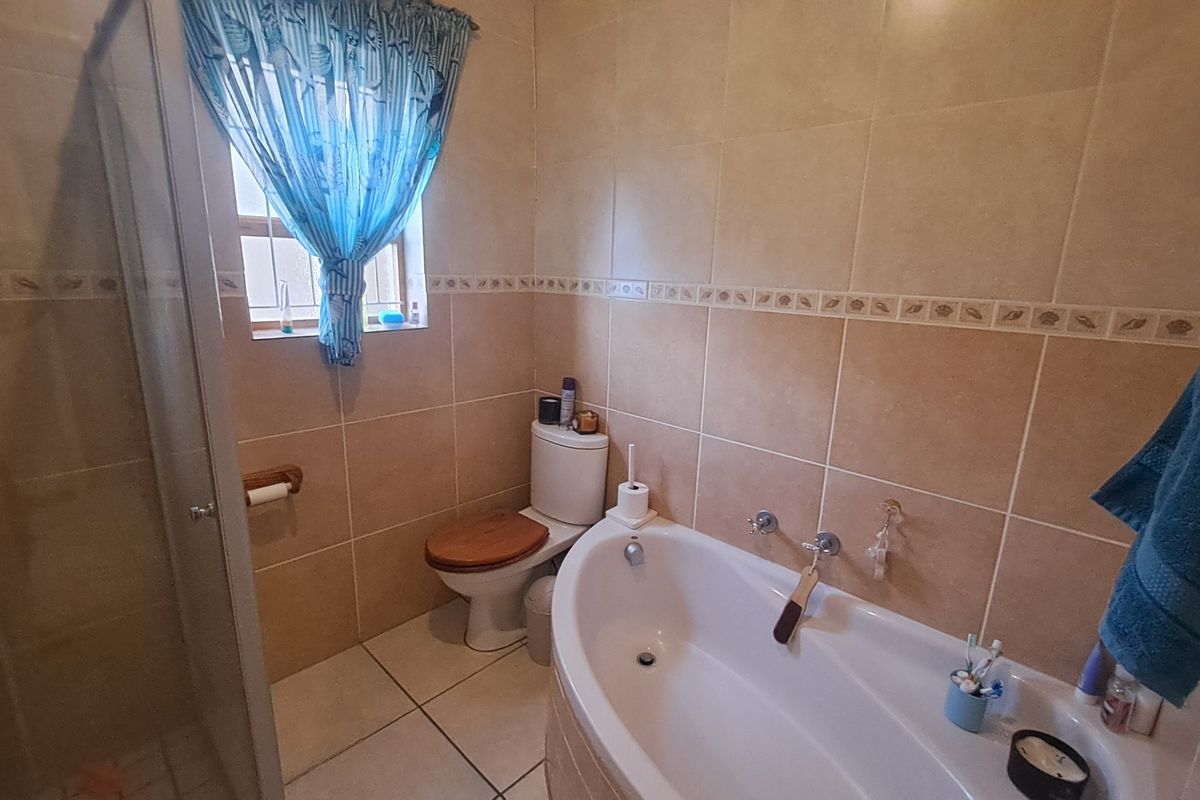 A functional bathroom featuring a bathtub, separate shower enclosure, and neutral ceramic wall and floor tiling.