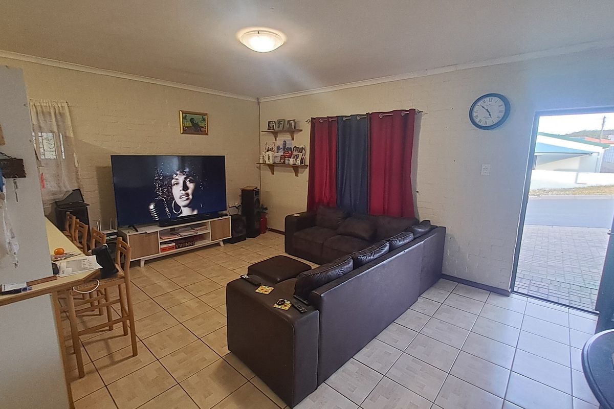 A functional living room featuring tiled flooring, painted brick walls, and direct access to the exterior.