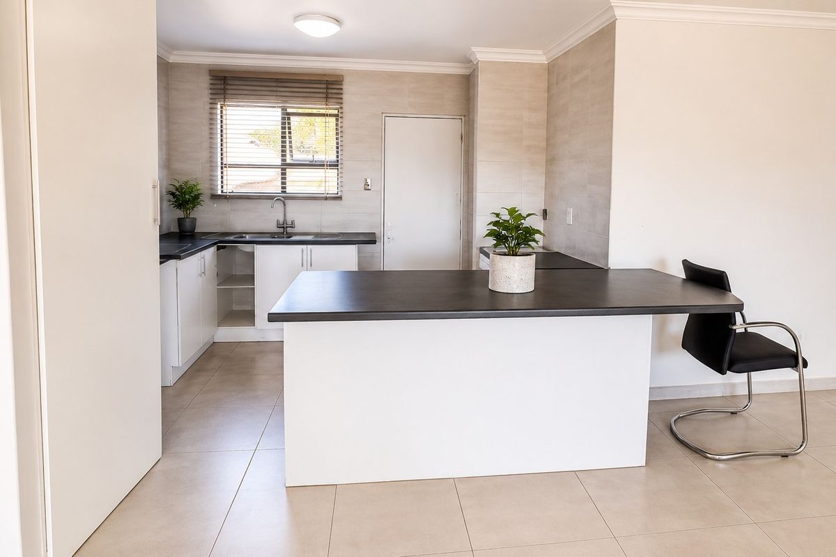 Modern kitchen featuring clean white cabinetry, dark laminate countertops, tiled flooring, and a functional breakfast bar island.