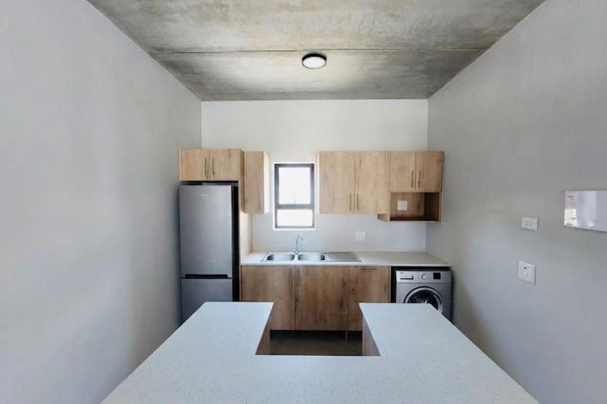 Modern kitchen featuring light wood cabinetry, stone-look countertops, a u-shaped breakfast bar, and an exposed concrete ceiling in a clean, minimalist space.