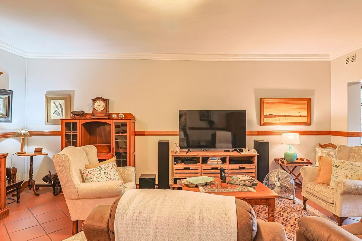 A comfortable living room featuring tiled flooring, decorative cornice detailing, and a chair rail, with access to an outdoor area through a security gate.