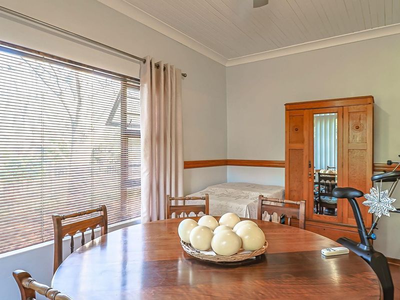 A dining room featuring timber window frames, venetian blinds, and a classic tongue and groove ceiling with a decorative timber dado rail.