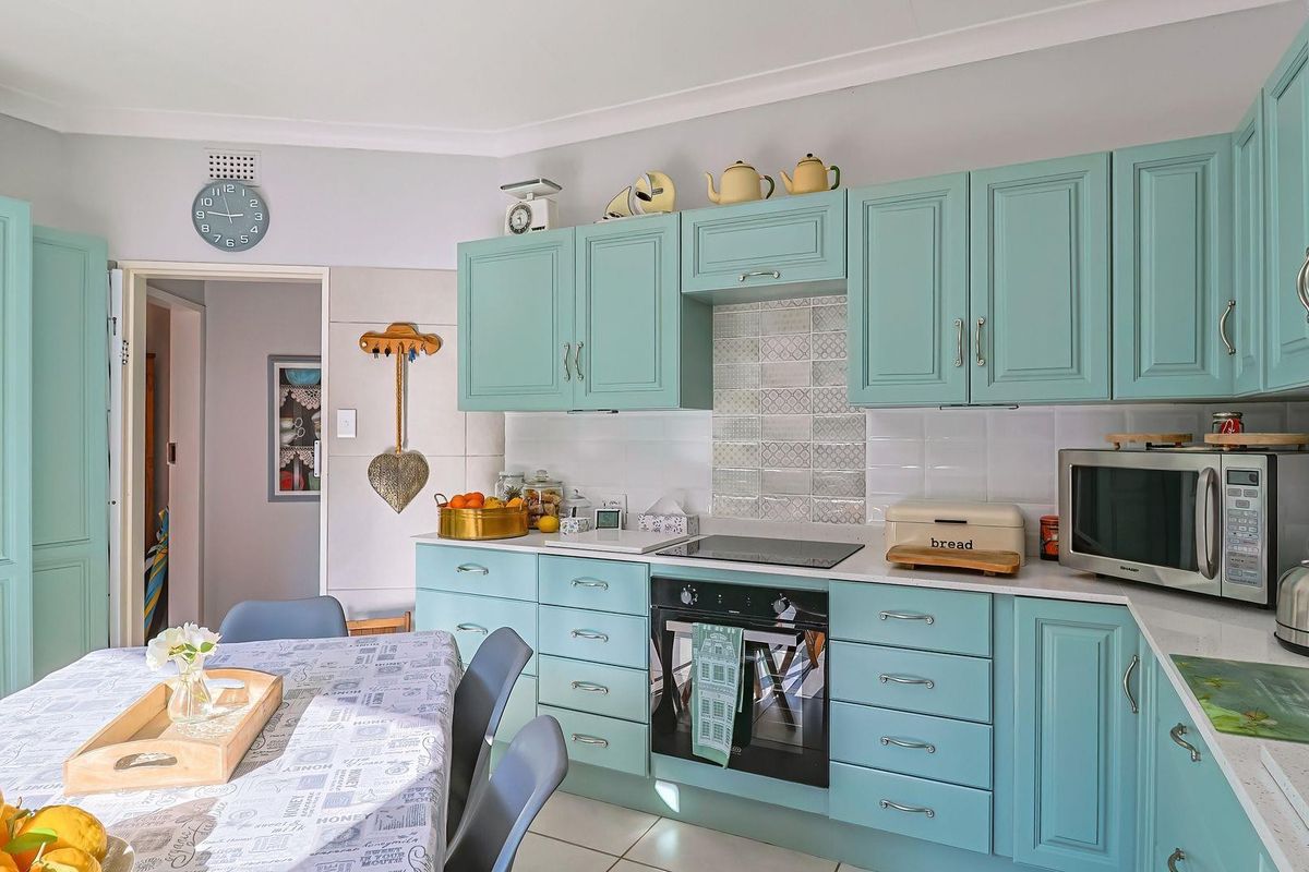 A functional kitchen featuring light blue cabinetry, stone countertops, a built-in oven, and a decorative tiled splashback.