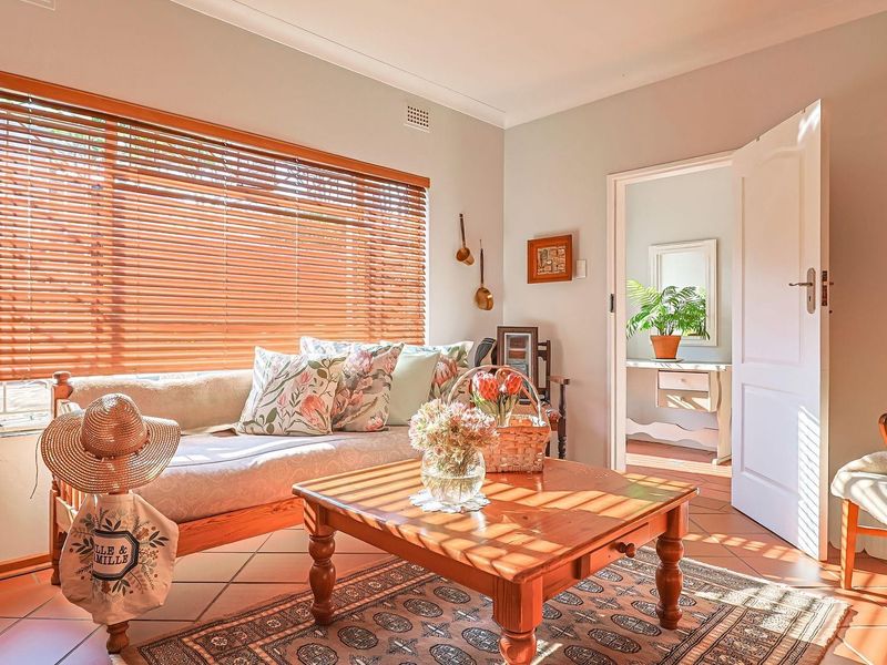 A bright living room featuring terracotta floor tiles, coved ceiling cornices, and wooden venetian blinds, offering a warm and inviting atmosphere.