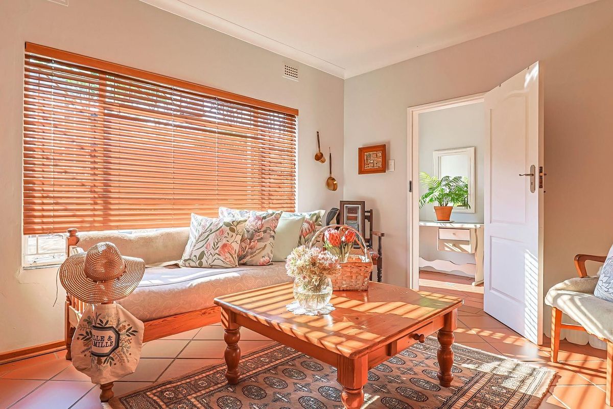 A bright living room featuring terracotta floor tiles, coved ceiling cornices, and wooden venetian blinds, offering a warm and inviting atmosphere.
