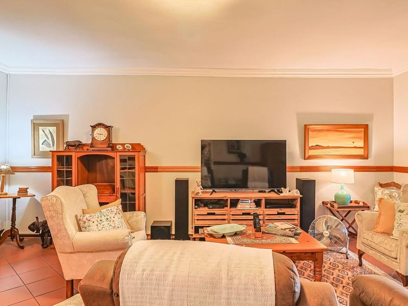 A comfortable living room featuring tiled flooring, decorative cornice detailing, and a chair rail, with access to an outdoor area through a security gate.