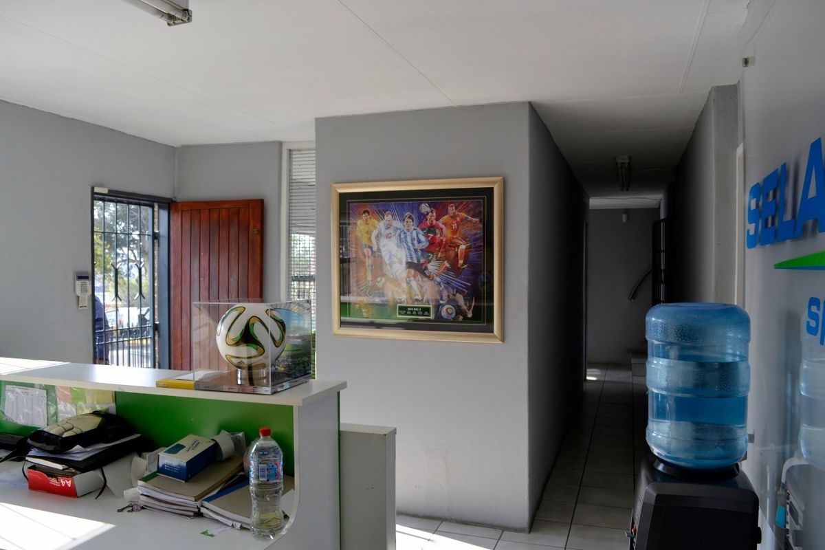 Entrance area featuring a reception desk, tiled flooring, and security gate access, providing a functional welcome space for the industrial property.