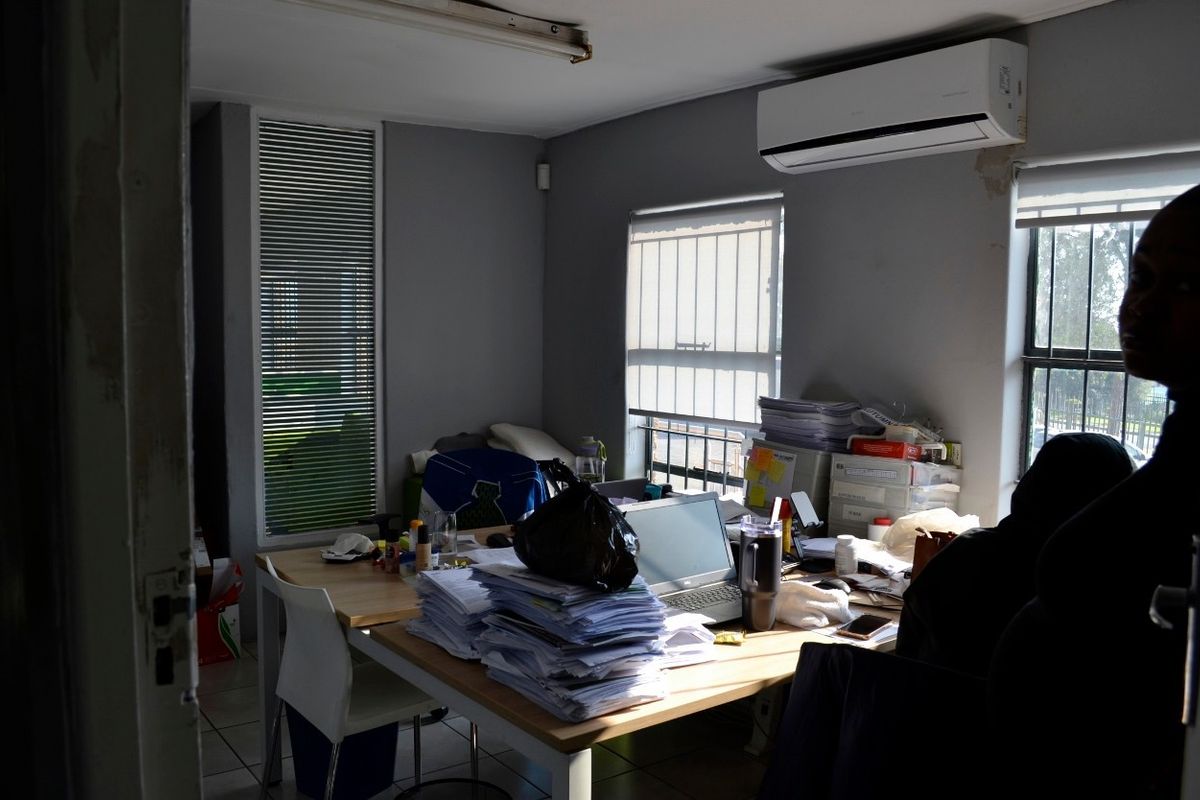 Functional office space featuring tiled flooring, split-system air conditioning, and security bars on windows, suitable for professional use.