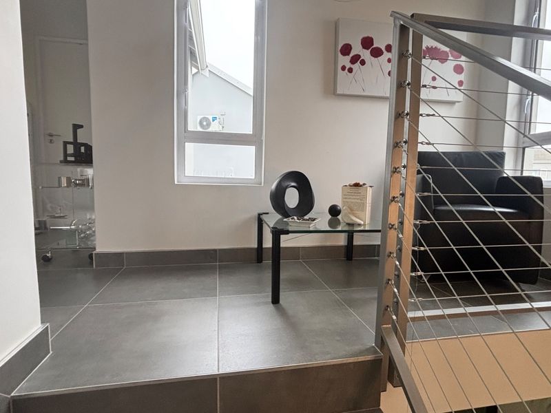 A bright landing area featuring modern grey floor tiles and a contemporary stainless steel cable balustrade overlooking the staircase.