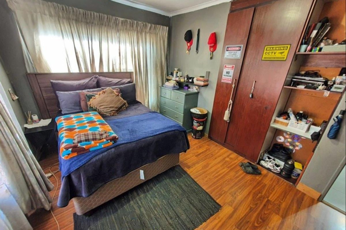 A bedroom featuring laminate flooring and a built-in wooden wardrobe with integrated shelving.