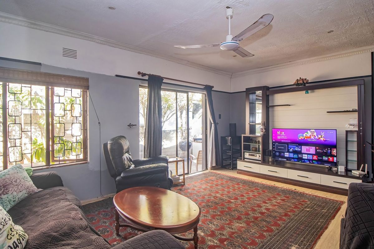 Spacious living room featuring a built-in media unit, ceiling fan, and sliding glass doors providing access to the outdoor area.