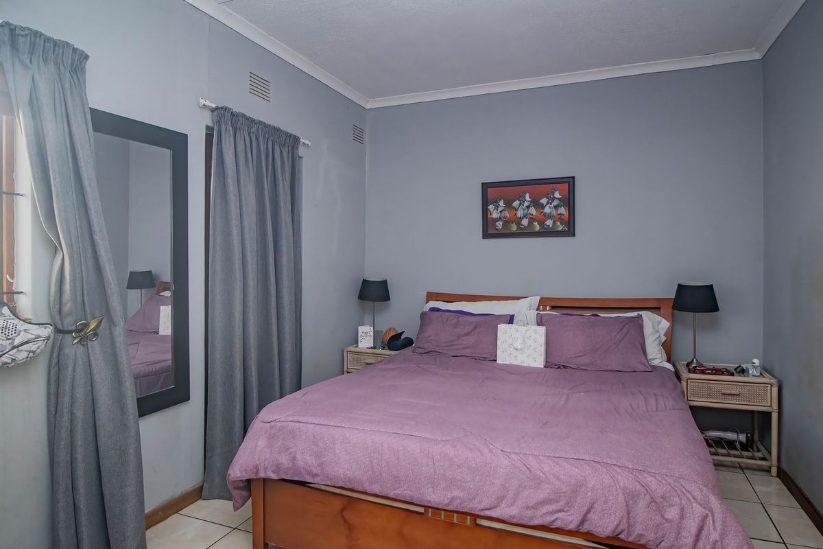 A functional bedroom featuring tiled flooring, neutral grey walls, and built-in curtain tracks, providing a simple and practical living space.