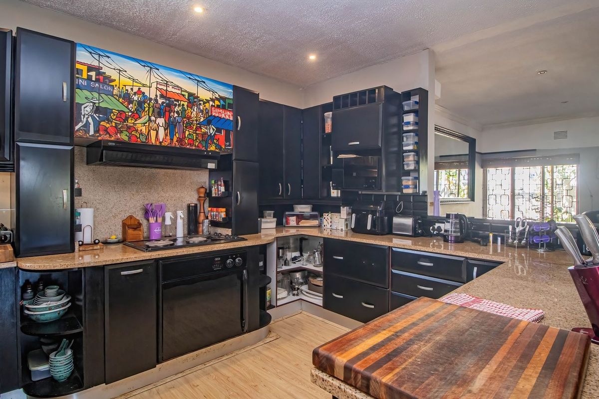 A functional kitchen featuring dark cabinetry, granite countertops, and integrated appliances, offering a solid foundation for a modern cosmetic update.