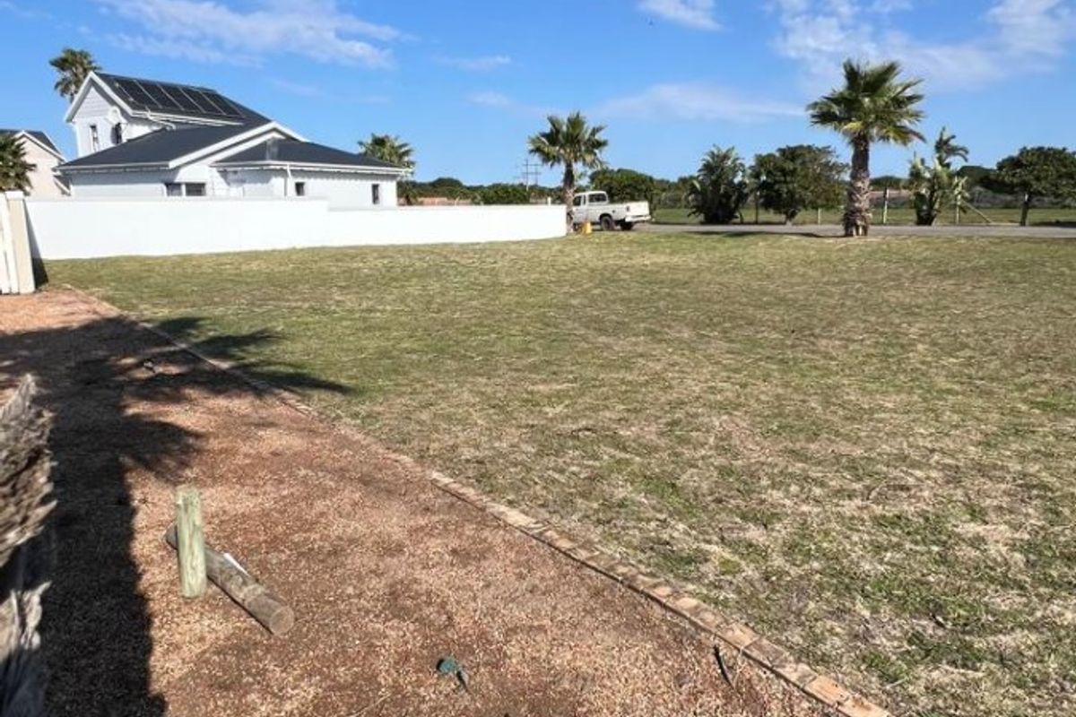 A clear, level residential plot featuring a well-maintained lawn, gravel border, and perimeter boundary wall.