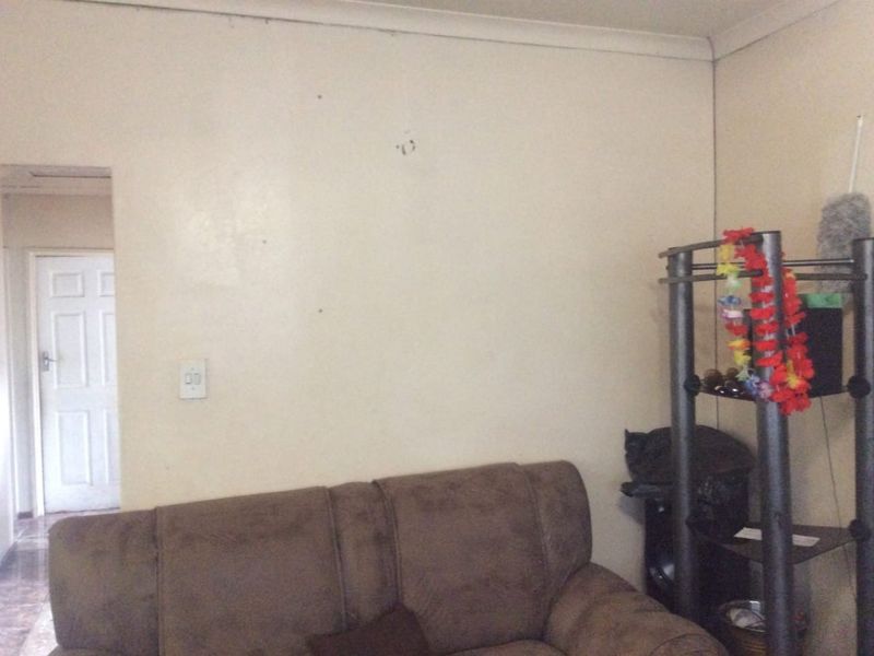 A living room area featuring plain walls with minor surface imperfections and a standard interior door leading to an adjacent space.