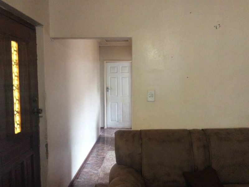 A view of an interior hallway with tiled flooring and access to adjacent rooms, showing signs of wear on the wall surfaces.