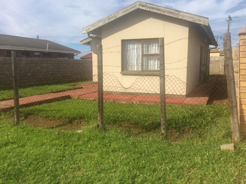Rear view of the property featuring a small tiled patio area, enclosed by wire mesh fencing and concrete block boundary walls.