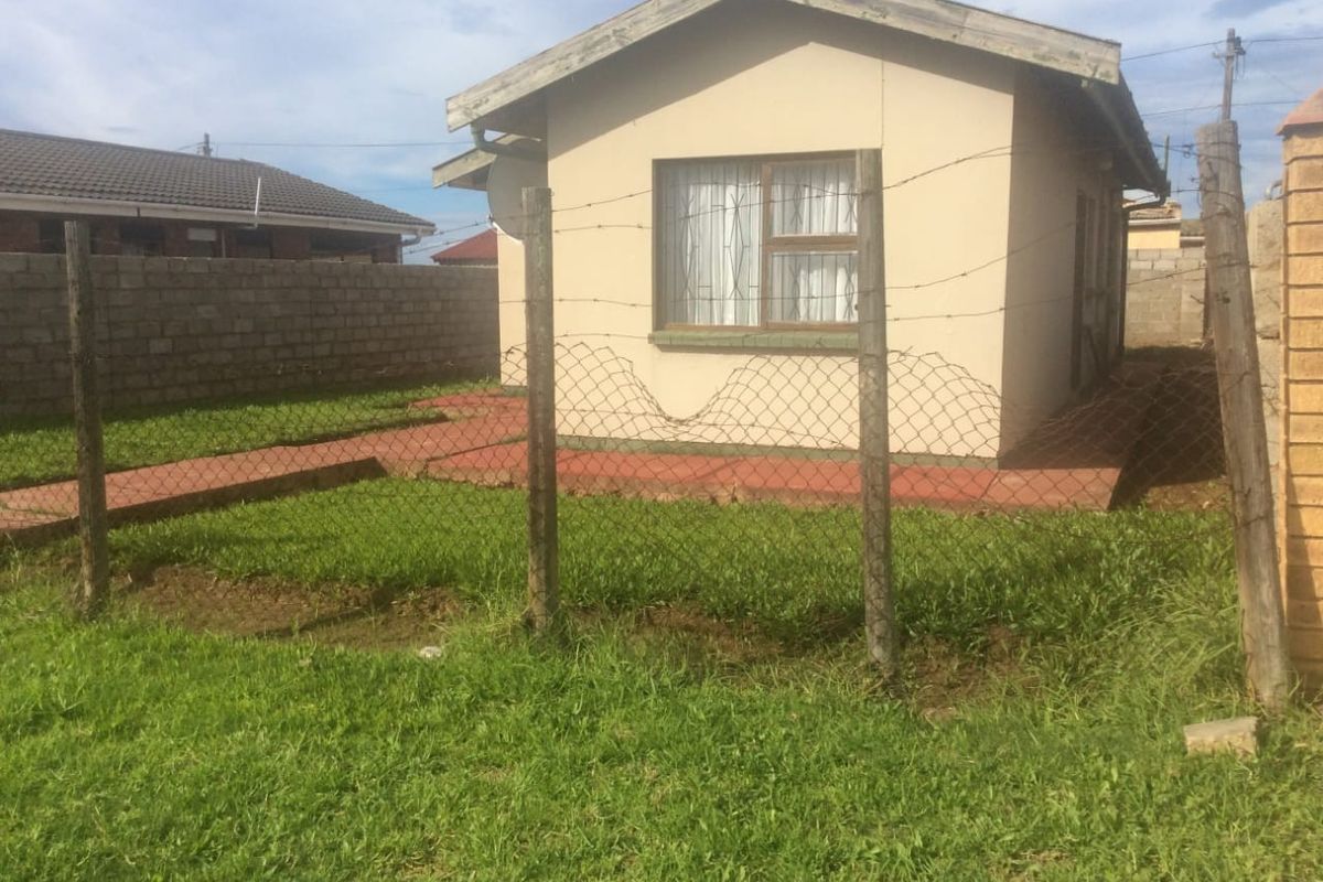 Rear view of the property featuring a small tiled patio area, enclosed by wire mesh fencing and concrete block boundary walls.