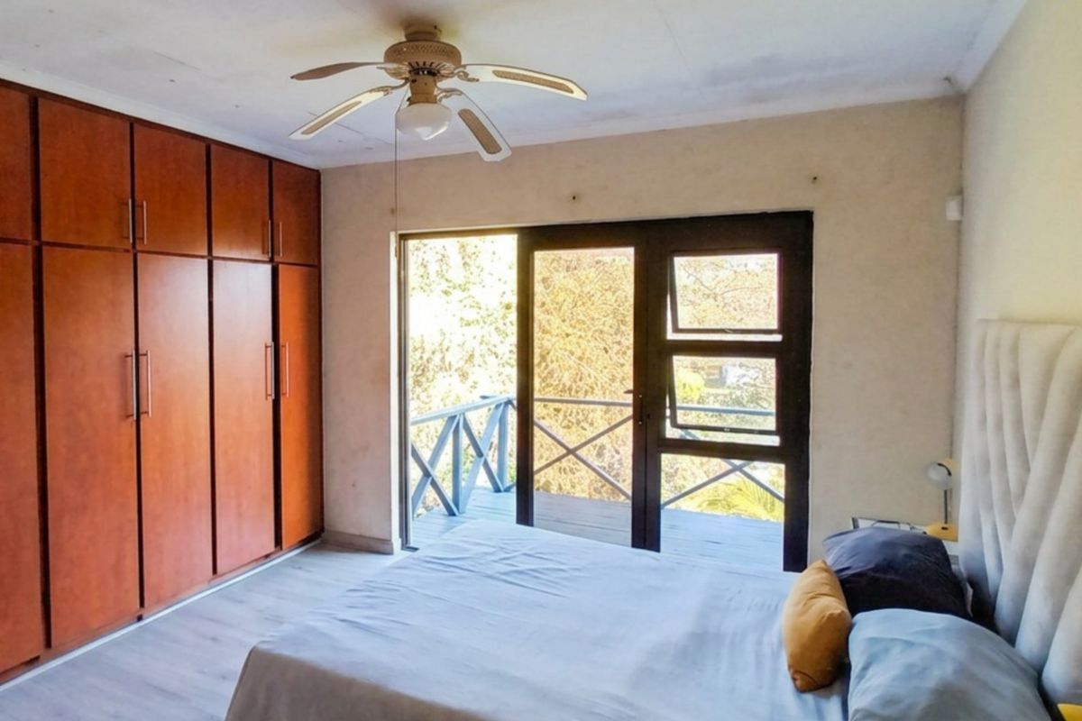Bedroom featuring built-in wooden cupboards, a ceiling fan, and sliding glass doors providing direct access to an outdoor balcony.