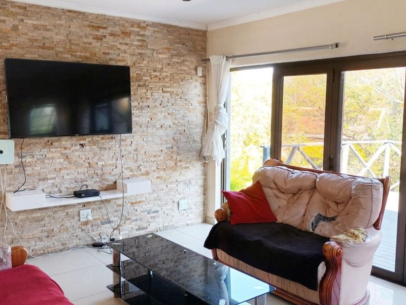 Living room featuring a textured stacked stone accent wall, tiled flooring, and large sliding glass doors providing natural light and access to the outdoors.