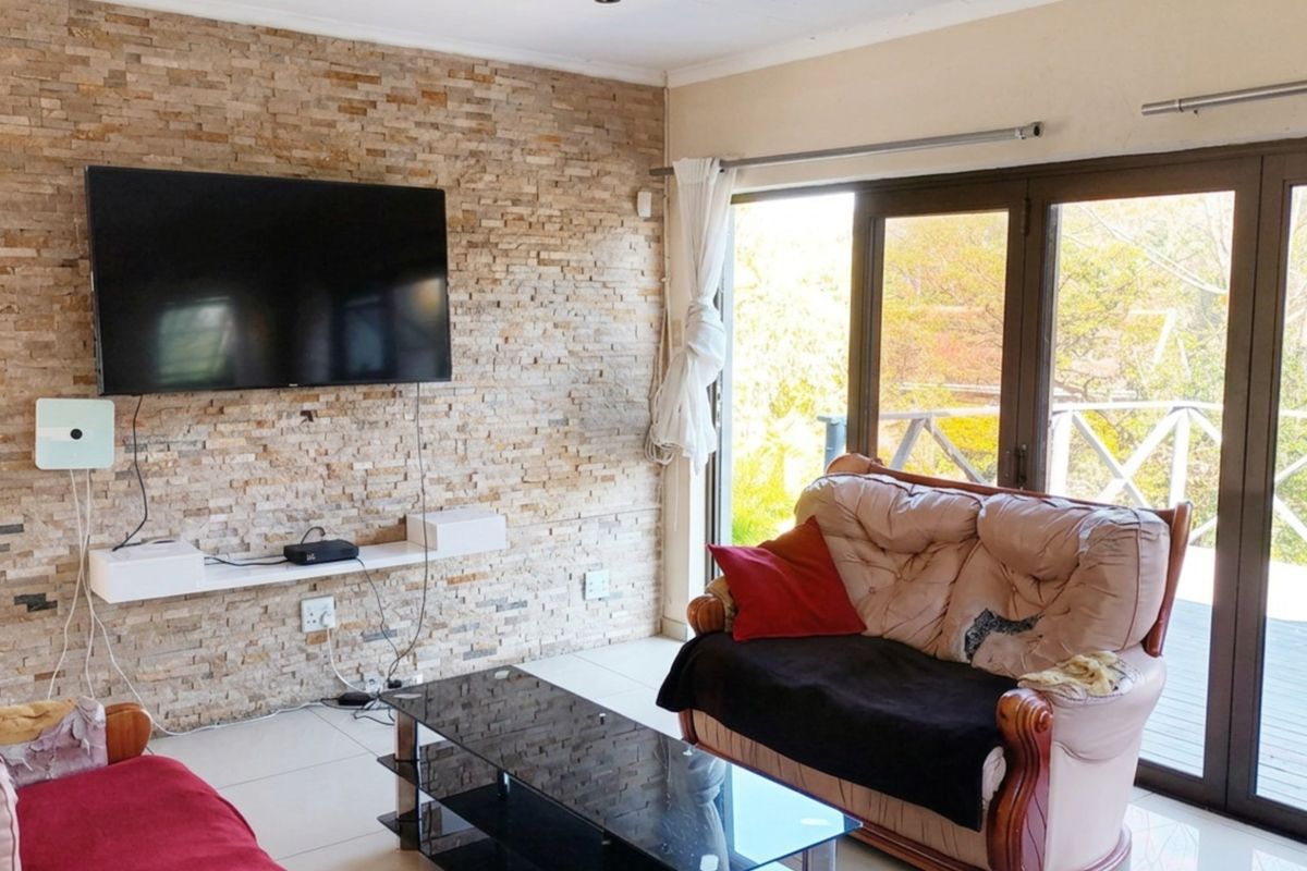 Living room featuring a textured stacked stone accent wall, tiled flooring, and large sliding glass doors providing natural light and access to the outdoors.