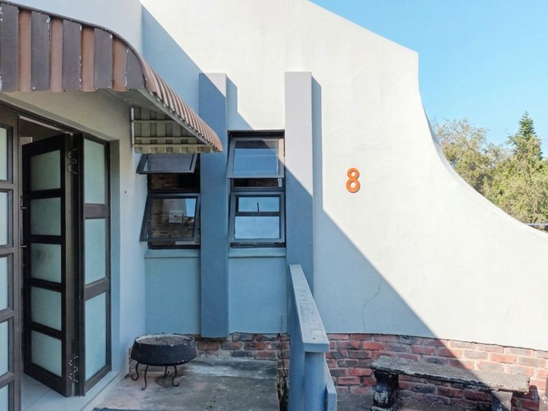 Front entrance area featuring a frosted glass door, top-hung windows, and a covered patio space with brick detailing.