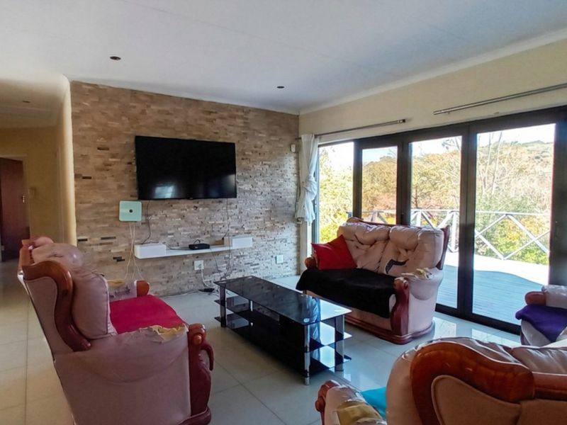 Spacious living room featuring a textured stone accent wall, tiled flooring, and large sliding glass doors providing natural light and access to the outdoors.