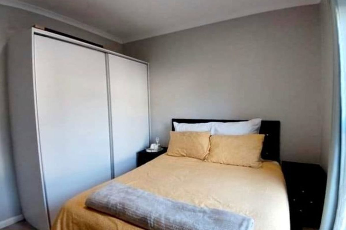 A compact bedroom featuring a built-in wardrobe with sliding doors and neutral wall finishes.