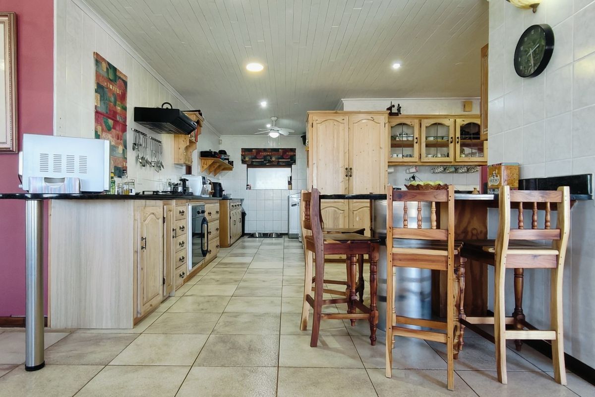 Spacious kitchen featuring extensive wooden cabinetry, granite countertops, a breakfast bar, and tiled flooring with integrated appliances.