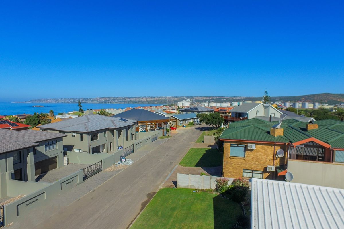 An aerial view of a coastal residential neighborhood, showcasing the street layout, surrounding properties, and proximity to the ocean.