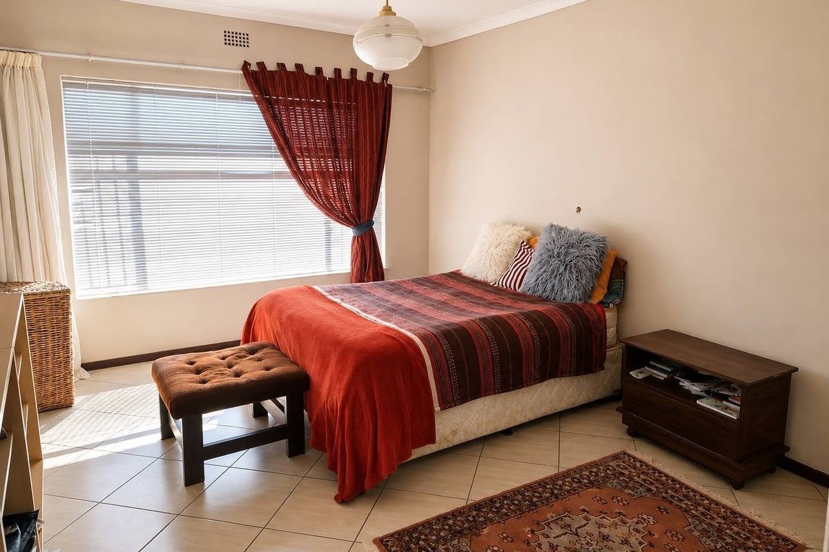 A bedroom featuring tiled flooring, a ceiling vent, and natural light from a large window.