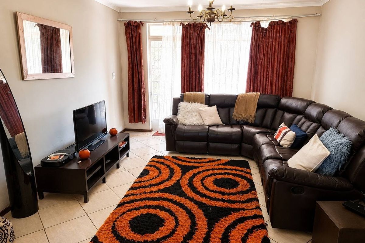 A comfortable living room featuring tiled flooring, a ceiling light fixture, and a sliding glass door providing access to the exterior.