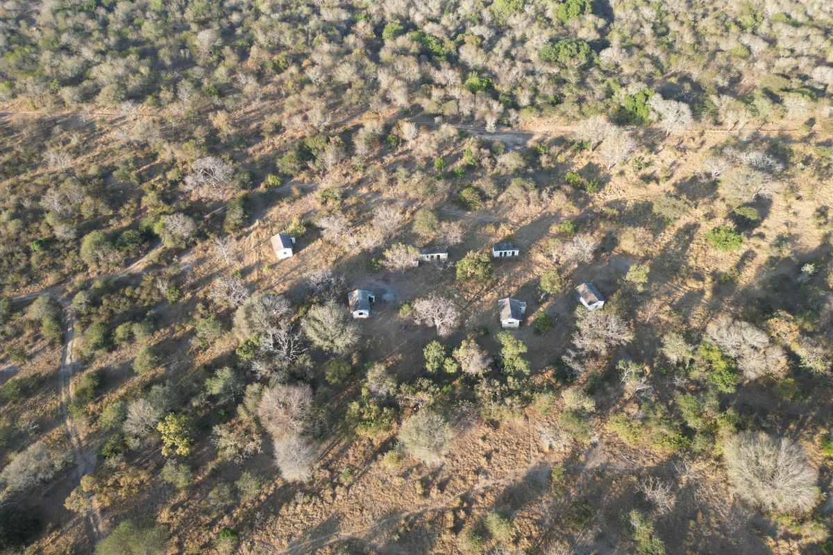 Aerial view of a rural farm property featuring multiple detached structures situated within a natural woodland landscape.